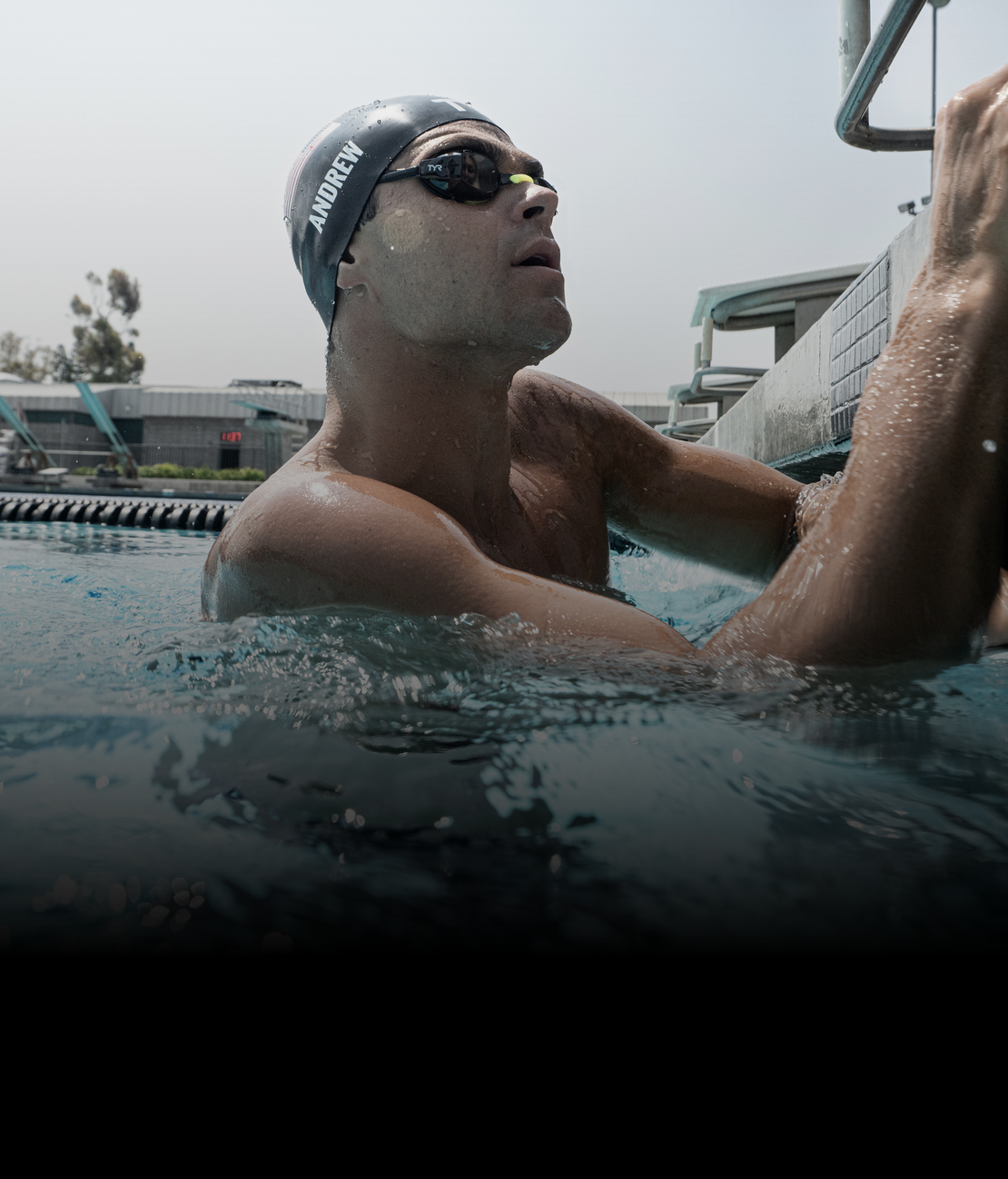 Swimmer wearing a cap and goggles, looking up from the pool